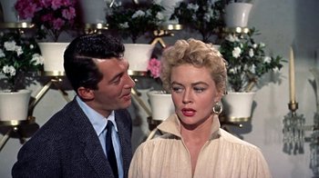 Movie still from “Artists and Models” (1955), directed by Frank Tashlin – A man standing next to a woman in front of flowers; Close Up shot, Over the shoulder angle