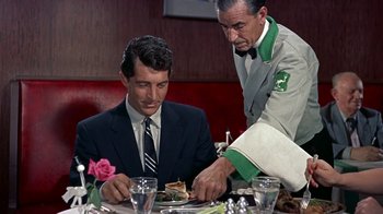 Movie still from “Artists and Models” (1955), directed by Frank Tashlin – A man sitting at a table with a plate of food in front of him; Medium shot, Over the shoulder angle