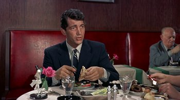 Movie still from “Artists and Models” (1955), directed by Frank Tashlin – A man sitting at a table with a sandwich in front of him; Medium shot, Over the shoulder angle