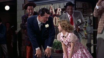 Movie still from “Artists and Models” (1955), directed by Frank Tashlin – A man and a girl in a dress and a man in a suit and tie; Medium shot, Over the shoulder angle