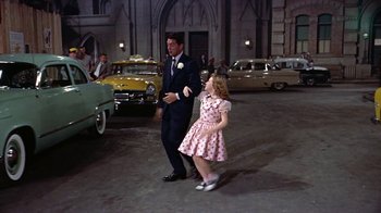 Movie still from “Artists and Models” (1955), directed by Frank Tashlin – A man and a little girl are walking in a parking lot; Wide shot, High angle