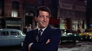 Movie still from “Artists and Models” (1955), directed by Frank Tashlin – A man wearing a suit and tie standing in front of a building; Close Up shot, Low angle