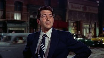 Movie still from “Artists and Models” (1955), directed by Frank Tashlin – A man wearing a suit and tie standing in front of a building; Close Up shot, Low angle
