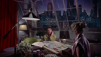 Movie still from “Artists and Models” (1955), directed by Frank Tashlin – Two women sitting at a table in front of a painting; Medium shot, Low angle