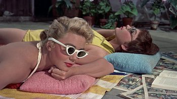 Movie still from “Artists and Models” (1955), directed by Frank Tashlin – Two women laying on the ground wearing sun glasses; Medium shot, High angle