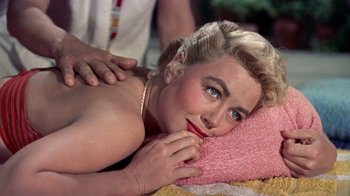 Movie still from “Artists and Models” (1955), directed by Frank Tashlin – A woman laying on a towel getting a back massage; Close Up shot, High angle