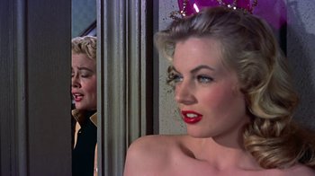 Movie still from “Artists and Models” (1955), directed by Frank Tashlin – A woman with blonde hair and red lipstick looking in a mirror; Close Up shot, Over the shoulder angle