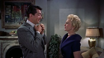 Movie still from “Artists and Models” (1955), directed by Frank Tashlin – A man and a woman standing next to each other in a room; Medium shot, Over the shoulder angle