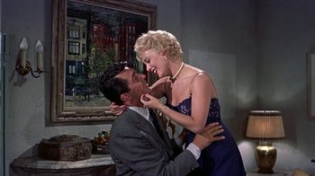 Movie still from “Artists and Models” (1955), directed by Frank Tashlin – A man and a woman are kissing in front of a painting; Medium shot, Low angle