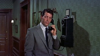 Movie still from “Artists and Models” (1955), directed by Frank Tashlin – A man in a suit and tie talking on a phone; Medium shot, Low angle