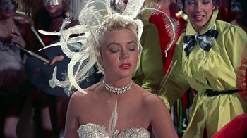 Movie still from “Artists and Models” (1955), directed by Frank Tashlin – A woman in a white dress with feathers on her head; Close Up shot, Over the shoulder angle