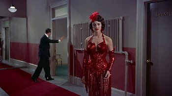 Movie still from “Artists and Models” (1955), directed by Frank Tashlin – A woman in a red sequined dress standing in front of a man; Medium shot, Low angle