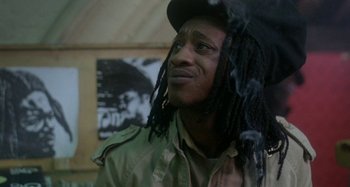Movie still from “Babylon” (1980), directed by Franco Rosso – A man with dreads smoking a cigarette in a room; Close Up shot, Low angle