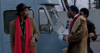 Movie still from “Babylon” (1980), directed by Franco Rosso – Two men are standing in front of a truck; Medium shot, Over the shoulder angle