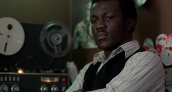 Movie still from “Babylon” (1980), directed by Franco Rosso – A man sitting in front of an old fashioned radio; Close Up shot, Low angle