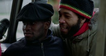 Movie still from “Babylon” (1980), directed by Franco Rosso – A couple of men sitting next to each other on a bench; Close Up shot, Over the shoulder angle
