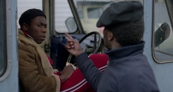 Movie still from “Babylon” (1980), directed by Franco Rosso – Two men sitting in a car talking to each other; Medium shot, Over the shoulder angle