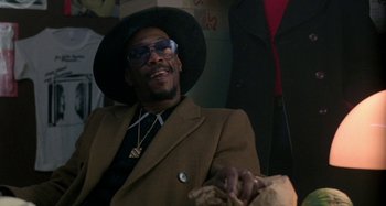 Movie still from “Babylon” (1980), directed by Franco Rosso – A man wearing a hat and a suit and tie; Close Up shot, Low angle