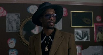 Movie still from “Babylon” (1980), directed by Franco Rosso – A man wearing a hat and sunglasses in a room; Close Up shot, Low angle