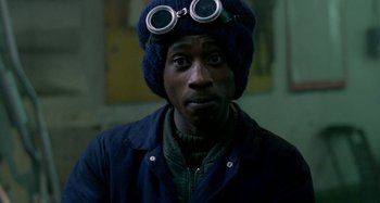 Movie still from “Babylon” (1980), directed by Franco Rosso – A man wearing a hat and goggles looks into the camera; Close Up shot, High angle