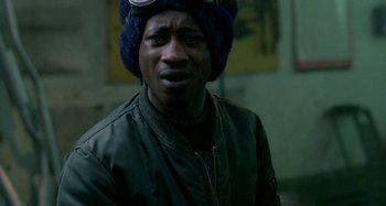 Movie still from “Babylon” (1980), directed by Franco Rosso – A man wearing a blue hat and a jacket; Close Up shot, Over the shoulder angle