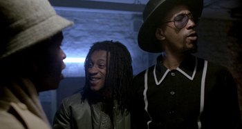 Movie still from “Babylon” (1980), directed by Franco Rosso – A group of men standing next to each other; Medium shot, Over the shoulder angle