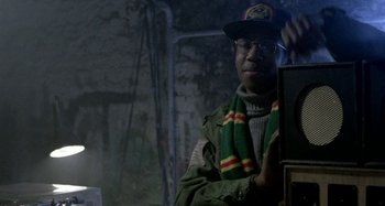 Movie still from “Babylon” (1980), directed by Franco Rosso – A man wearing a hat and a scarf; Close Up shot, Over the shoulder angle