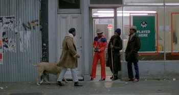 Movie still from “Babylon” (1980), directed by Franco Rosso – A group of people standing on a sidewalk; Wide shot, Low angle