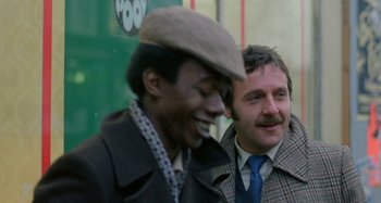 Movie still from “Babylon” (1980), directed by Franco Rosso – A man in a brown hat and a man in a brown jacket; Close Up shot, Over the shoulder angle