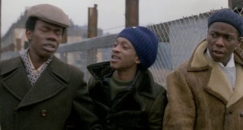 Movie still from “Babylon” (1980), directed by Franco Rosso – A group of young men standing next to each other on a bridge; Medium shot, Over the shoulder angle