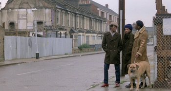 Movie still from “Babylon” (1980), directed by Franco Rosso – A man and a woman standing next to each other on the side of the street; Wide shot, Low angle