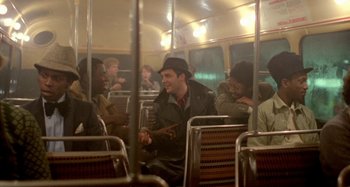 Movie still from “Babylon” (1980), directed by Franco Rosso – A group of people riding on a bus together; Wide shot, High angle