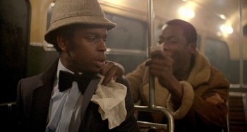 Movie still from “Babylon” (1980), directed by Franco Rosso – A man with a bow tie on a bus; Close Up shot, Over the shoulder angle
