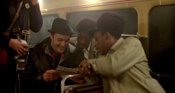 Movie still from “Babylon” (1980), directed by Franco Rosso – A group of men standing next to each other on a train; Medium shot, High angle