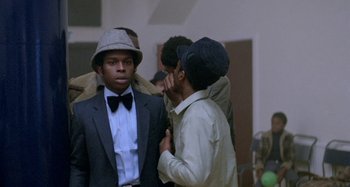 Movie still from “Babylon” (1980), directed by Franco Rosso – A group of young men standing next to each other in a room; Close Up shot, Low angle