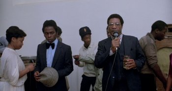 Movie still from “Babylon” (1980), directed by Franco Rosso – A group of men standing around a microphone; Medium shot, Low angle