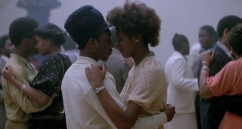Movie still from “Babylon” (1980), directed by Franco Rosso – A man and a woman are dancing in a crowd; Medium shot, Low angle