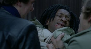 Movie still from “Babylon” (1980), directed by Franco Rosso – A man holding a blanket over a person's face; Close Up shot, High angle