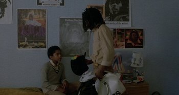 Movie still from “Babylon” (1980), directed by Franco Rosso – Two young men sitting on the floor in front of a wall; Medium shot, Over the shoulder angle