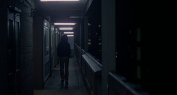 Movie still from “Babylon” (1980), directed by Franco Rosso – A person walking down a long hallway at night; Wide shot, High angle