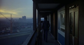 Movie still from “Babylon” (1980), directed by Franco Rosso – A person walking on a balcony with a view of a city; Wide shot, High angle