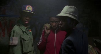 Movie still from “Babylon” (1980), directed by Franco Rosso – A group of men standing next to each other in a dark room; Medium shot, Low angle