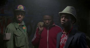 Movie still from “Babylon” (1980), directed by Franco Rosso – A group of men standing next to each other in a room; Medium shot, Low angle