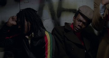 Movie still from “Babylon” (1980), directed by Franco Rosso – Two men sitting next to each other in a room; Medium shot, Low angle