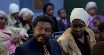 Movie still from “Babylon” (1980), directed by Franco Rosso – A man and a woman sitting next to each other in a room; Close Up shot, Low angle