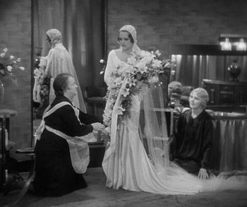 Movie still from “Bad Girl” (1931), directed by Frank Borzage – A woman kneeling down next to a woman holding a bouquet of flowers; Wide shot, High angle