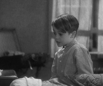 Movie still from “Bad Girl” (1931), directed by Frank Borzage – A young boy sitting in a chair in a room; Medium shot, High angle