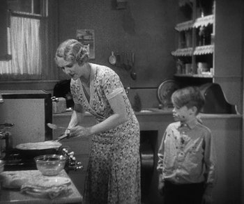 Movie still from “Bad Girl” (1931), directed by Frank Borzage – An old photo of a woman and a boy in a kitchen; Medium shot, High angle
