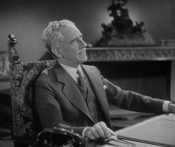 Movie still from “Bad Girl” (1931), directed by Frank Borzage – An older man sitting at a desk in a suit and tie; Medium shot, Low angle