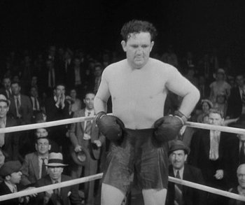 Movie still from “Bad Girl” (1931), directed by Frank Borzage – An old photo of a man standing in a boxing ring; Medium shot, Low angle